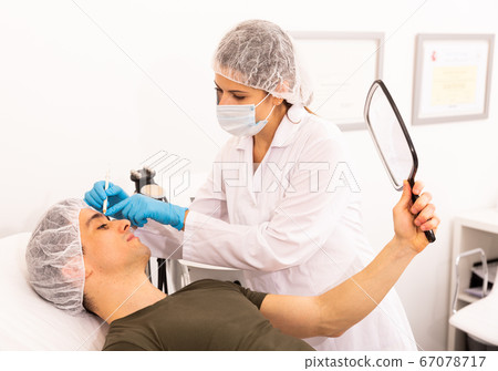 Cosmetologist giving consultation to male patient 67078717