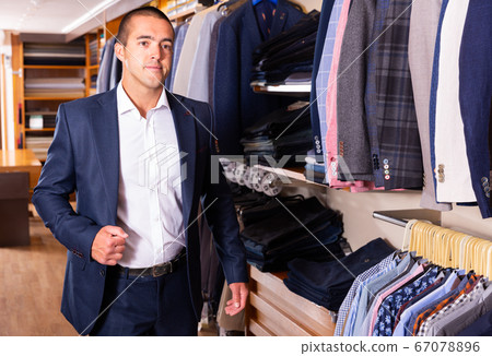 Portrait of male client choosing classic jacket in the mall 67078896