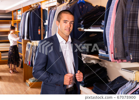 Portrait of male client choosing classic jacket in the mall Portrait of male client choosing classic jacket in the mall 67078900