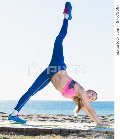 Beautiful girl stretching muscles on the sand 67079067