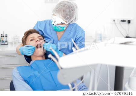 Young man on dental checkup in modern dentist office 67079111