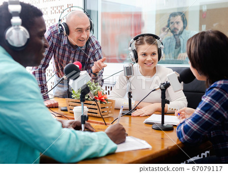 Multinational group of cheerful young adults emotionally discussing in radio studio 67079117