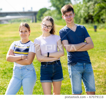 Positive teenagers posing on the spring park lawn 67079118