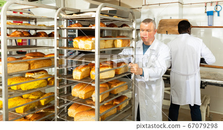 Baker carrying fresh bread on trolley 67079298