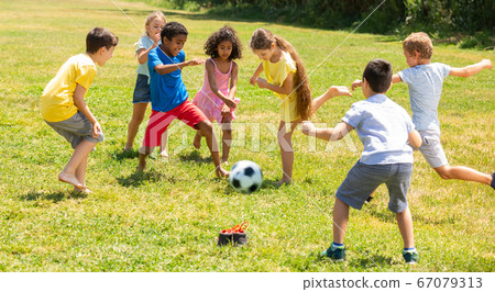 Company of glad children playing football on the playground Company of glad children playing football on the playground 67079313