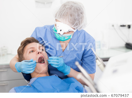 Young man on dental checkup in modern dentist office Young man on dental checkup in modern dentist office 67079437
