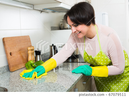 Positive housewife polishing kitchen surfaces Positive housewife polishing kitchen surfaces 67079511