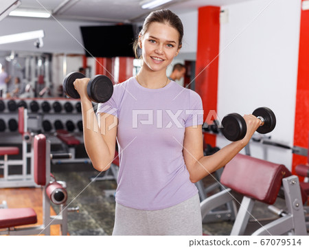 Woman doing exercises with dumbbells Woman doing exercises with dumbbells 67079514