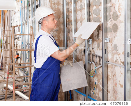 Focused construction worker picking ceramic tiles for interior finish of repairable room 67079516