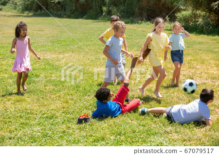 Cheerful children are jogning with ball on playground Cheerful children are jogning with ball on playground 67079517