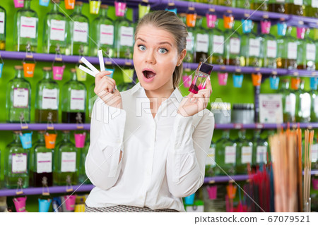 Surprised girl choosing perfume with paper tester Surprised girl choosing perfume with paper tester 67079521