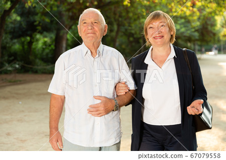 Elderly couple enjoying walk in park 67079558