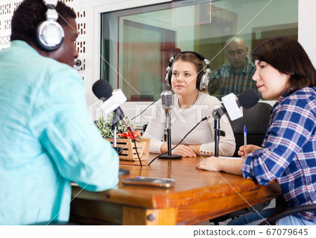 Multinational group of cheerful young adults emotionally discussing in radio studio Multinational group of cheerful young adults emotionally discussing in radio studio 67079645