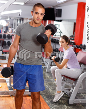 Portrait of muscular guy lifting dumbbells Portrait of muscular guy lifting dumbbells 67079649