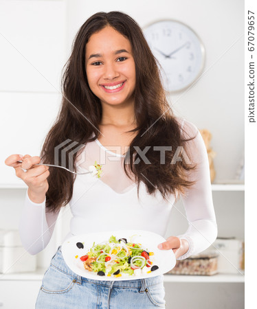 Smiling young girl eating tasty salad Smiling young girl eating tasty salad 67079657