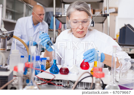 Female biochemists mixing chemicals Female biochemists mixing chemicals 67079667