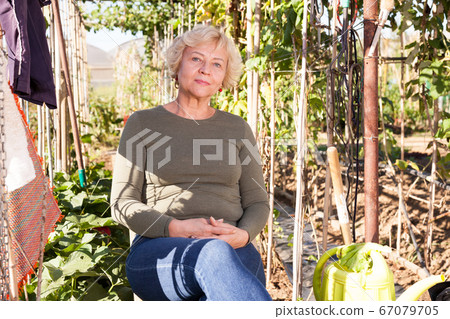 Woman resting on chair in garden Woman resting on chair in garden 67079705