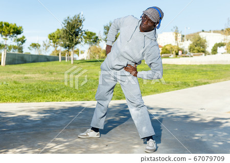 Athletic african american male performs warm-up exercises in park Athletic african american male performs warm-up exercises in park 67079709