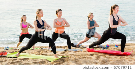 Group of young females performing yoga Group of young females performing yoga 67079711