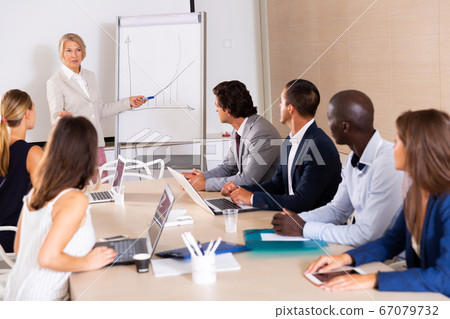 Woman reading out report to colleagues Woman reading out report to colleagues 67079732