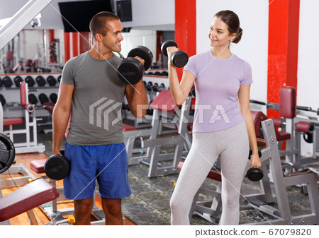 Man and woman posing with dumbbells 67079820