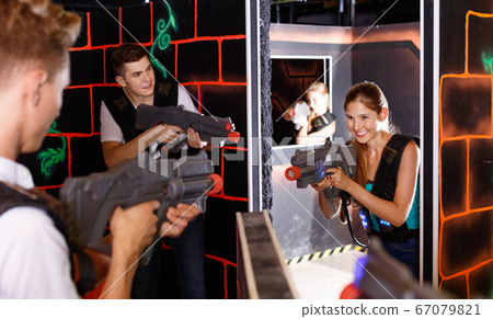 Two laser tag teams playing enthusiastically and aiming at each other in dark room Two laser tag teams playing enthusiastically and aiming at each other in dark room 67079821