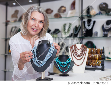 Adult woman chooses jewelry from turquoise jewelery in the store Adult woman chooses jewelry from turquoise jewelery in the store 67079855