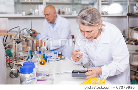 Female biochemists mixing chemicals Female biochemists mixing chemicals 67079986