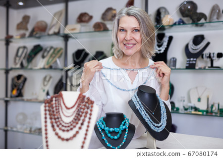 Adult woman chooses jewelry from turquoise jewelery in the store Adult woman chooses jewelry from turquoise jewelery in the store 67080174
