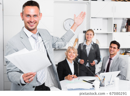 Happy entrepreneur with papers standing in office Happy entrepreneur with papers standing in office 67080291