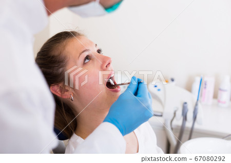 Stomatologist in white is taking examination of an adult woman on the chair Stomatologist in white is taking examination of an adult woman on the chair 67080292