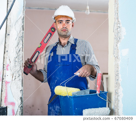 Portrait of man which is standing with spirit level and bucket Portrait of man which is standing with spirit level and bucket 67080409