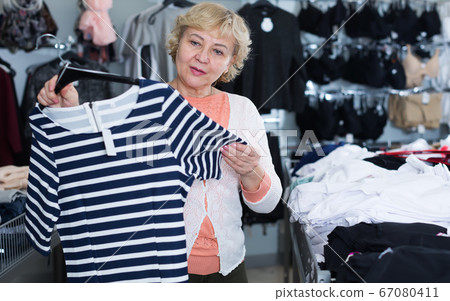 Modern woman consumer choosing striped dress Modern woman consumer choosing striped dress 67080411