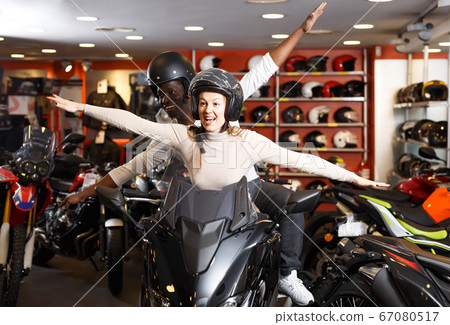 Positive young couple laughing sitting on bike Positive young couple laughing sitting on bike 67080517