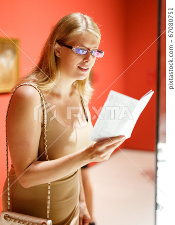 Woman with booklet looking at exhibits 67080751
