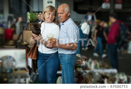 Smiling mature spouses buying retro handicrafts on flea market Smiling mature spouses buying retro handicrafts on flea market 67080755