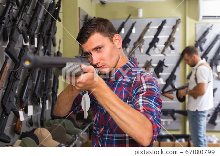 Portrait of adult male which is choosing air-powered gun 67080799