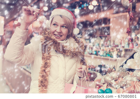 Woman is preparing for Christmas and choosing balls on the tree 67080801