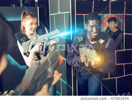 Modern people of different nationalities with laser pistols play Modern people of different nationalities with laser pistols play 67081034