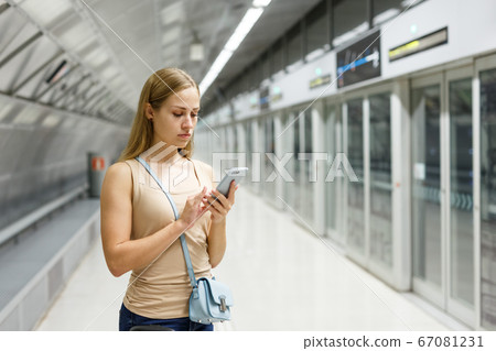 Girl using phone on subway station 67081231