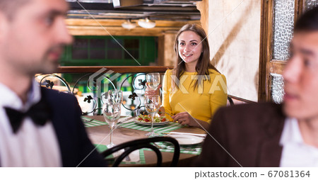 Elegant female is having dinner and observing for talk of two businessmen Elegant female is having dinner and observing for talk of two businessmen 67081364
