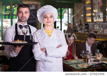 Portrait of male waiter and female cook who are welcoming clients Portrait of male waiter and female cook who are welcoming clients 67081498