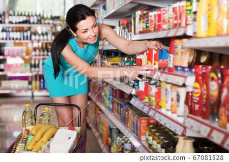Female choosing jar of canned tomato paste 67081528