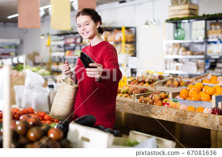 Beautiful girl buying aubergines at market 67081636