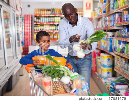 Happy friendly African family of father and tween son shopping together in supermarket 67081676