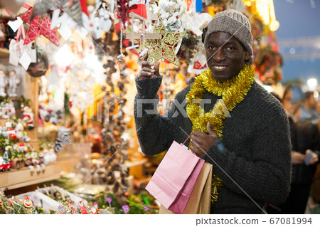 Guy choosing Christmas decorations Guy choosing Christmas decorations 67081994