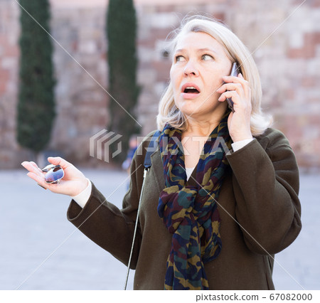Angry woman is talking by phone on the street Angry woman is talking by phone on the street 67082000