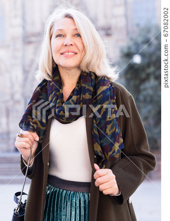 Elegant mature woman is posing in time walking on the street of old city 67082002