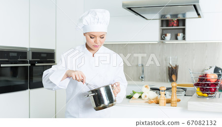 Female cook is making soup on her work place in the kitchen Female cook is making soup on her work place in the kitchen 67082132