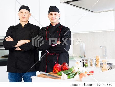 Young male chefs in black uniform standing near workplace 67082330